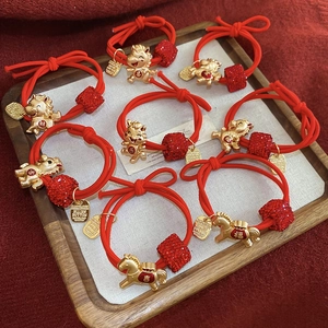 Détail de huit élastiques rouges avec pendentif cheval doré et symboles de chance