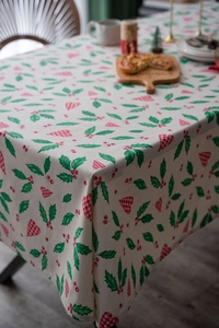Macro detail of Christmas tablecloth featuring holly leaves and red heart patterns