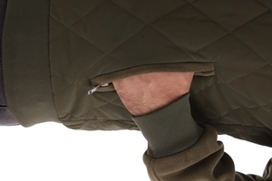 Detail of olive green diamond quilted jacket featuring zipper pocket and ribbed hem