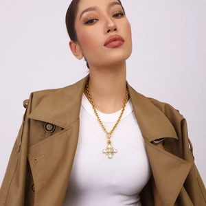 Close-up of gold cross necklace with white pearl and square zircon worn by a model