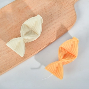Velas aromáticas geométricas en crema y naranja claro con textura sobre madera
