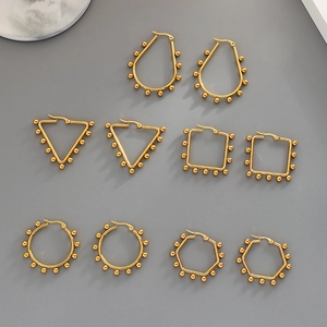 Flat lay of five pairs of golden geometric hoop earrings with small bead detail ornaments
