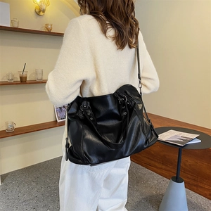 Black large capacity faux leather tote bag with shoulder strap shown in a lifestyle setting