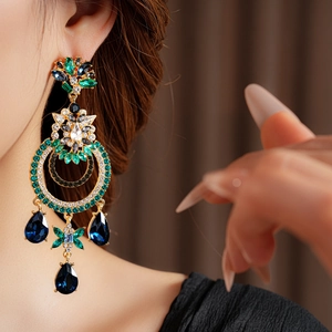 Détail macro de boucles d'oreilles vintage dorées avec gemmes vertes et bleues sur mannequin