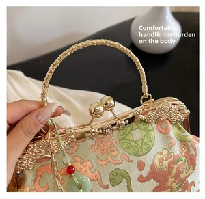 Close-up of traditional embroidery texture and jade pendant on green retro handbag