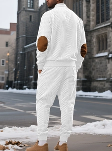 Detail view of white knitted tracksuit featuring textured diamond pattern and brown elbow patches