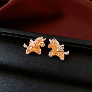 Macro shot of gold unicorn earrings featuring amber faceted stones and zircon details