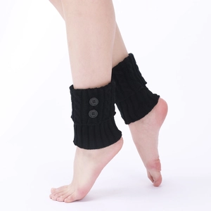 Detailed view of black cable-knit leg warmers with decorative buttons on female ankles
