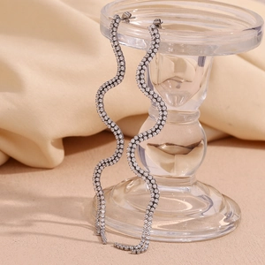 Macro detail of silver S-shape wavy drop earrings with glittering zircon stones