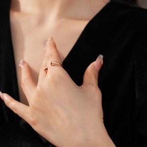 Gros plan d'une bague double gourde en or rose avec détail de coeur rouge sur doigt