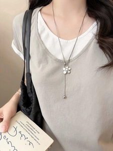 Detail of silver five-petal flower necklace with pearl inlay and long tassel snake chain