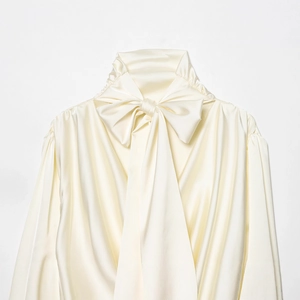 Blouse élégante en satin blanc cassé avec nœud au col montant et fini soyeux