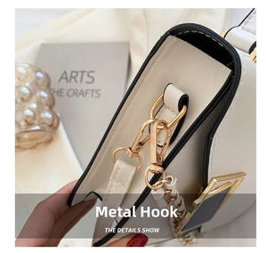 Makroaufnahme von goldenem D-Ring und Metallverschluss an cremeweißer Lederhandtasche
