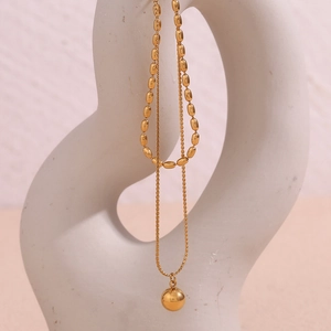 Detail of a minimalist double-layer 18K gold-plated beaded necklace with spherical pendant