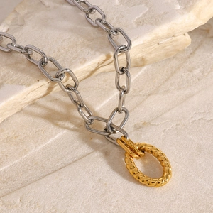 Close-up of two-tone stainless steel chain necklace with golden twisted ring pendant