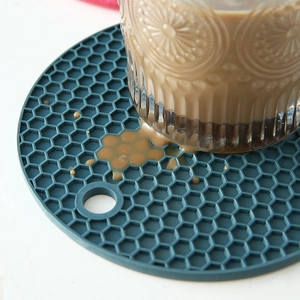 Round dark blue honeycomb silicone coaster for table protection with glass on white surface
