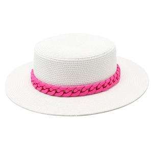 Detail of white boater straw hat featuring a vibrant pink resin chain decoration