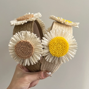 Close-up of handmade raffia woven headbands with 3D floral designs in beige and yellow