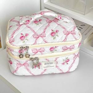 Detail of pink bow and flower quilted makeup bag featuring dual-layer storage and metal zippers