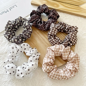 Close-up of a 5-piece floral and checkered fabric scrunchies set on a wooden tray