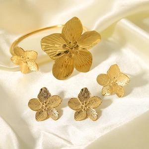 Macro detail of golden flower jewelry set with brushed metal texture on satin