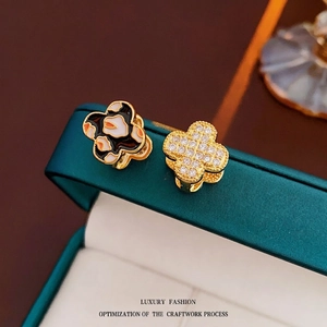 Detailed macro view of four-leaf clover earrings with leopard enamel and zircon inlay