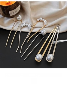 Detail of U-shaped gold and silver hair pins with elegant white imitation pearls