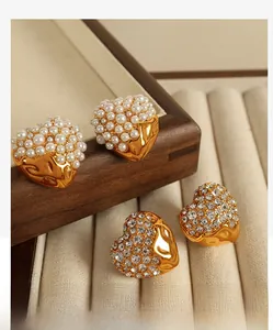 Detailed macro view of gold-plated heart earrings with inlaid pearls and zircon stones