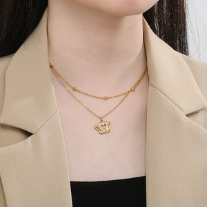 Detail of layered gold crown pendant necklace featuring rhinestones on a female model
