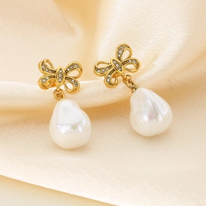 Golden bow earrings with pavé diamonds and shell pearls on premium beige silk background