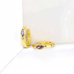 Gros plan de boucles d'oreilles huggie dorées avec zircon violet taille marquise