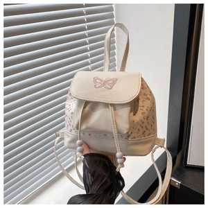 Detail of butterfly embroidery and floral patchwork on ivory PU leather backpack