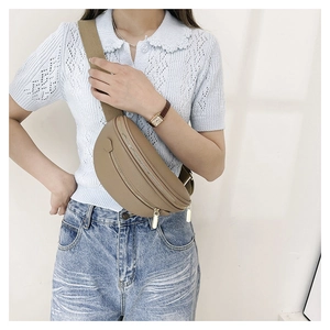 Détail du sac ceinture en cuir marron clair avec sangle large et boucles dorées