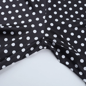 Détail du tissu élastique avec imprimé à pois blancs et coutures de finition précises