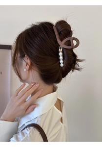 Pince à cheveux mate marron avec perles blanches sur une coiffure élégante relevée