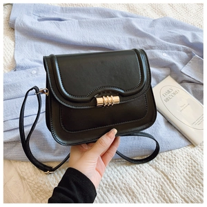 Gros plan sur un sac besace en cuir noir doté d'un fermoir rotatif en métal doré