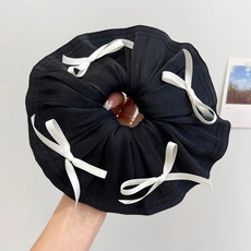 Detail of a black fabric hair scrunchie featuring multiple white decorative bows
