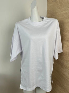 Detail of white oversized T-shirt featuring side slit hem and soft cotton texture