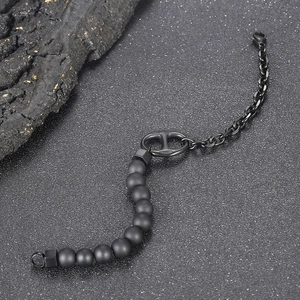 Black beaded and polished titanium steel bracelet with a pig nose link on rock background