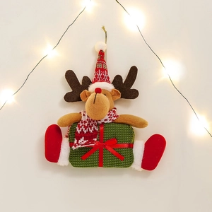 Plush Christmas reindeer ornament with red knit hat and scarf in warm festive lighting