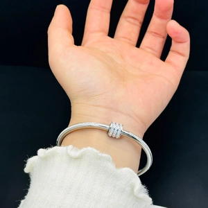 Dettaglio di un bracciale rigido argento con anelli incastonati di cristalli sul polso