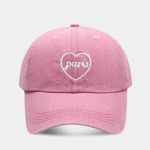 Close-up of pink washed cotton baseball cap featuring white heart and Paris embroidery