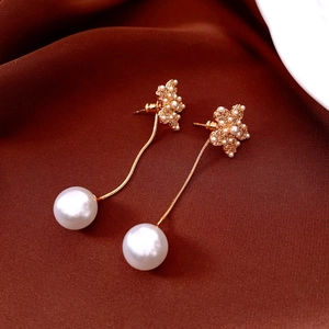Detailed macro of 18k gold flower earrings with white pearls on red silk fabric