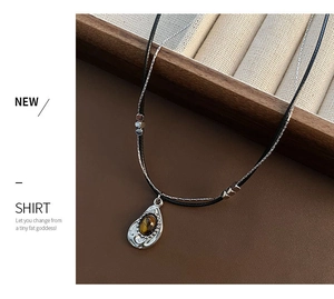 Detail of vintage double-layer necklace with a tiger eye stone pendant on brown leather