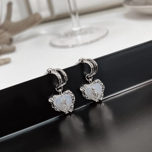 Macro shot of silver heart earrings with white opal stone and zircon accents