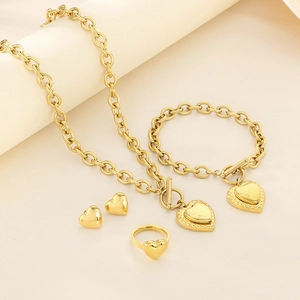 Detailed set of gold stainless steel heart necklace, bracelet, earrings and ring on beige fabric