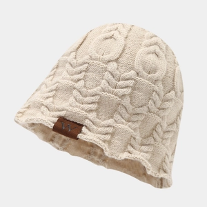 Détail macro de la maille torsadée crème et du patch en cuir sur ce bonnet d'hiver