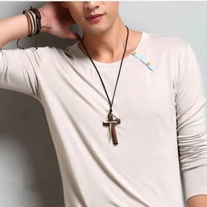 Detail of vintage wooden and alloy double-layer cross pendant on long sweater chain