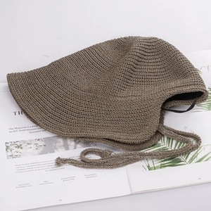 Detail of dark khaki woven sun hat with windproof chin strap on a magazine background