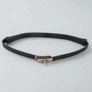 Detail of minimalist black pebbled leather belt with golden rotating metal lock buckle